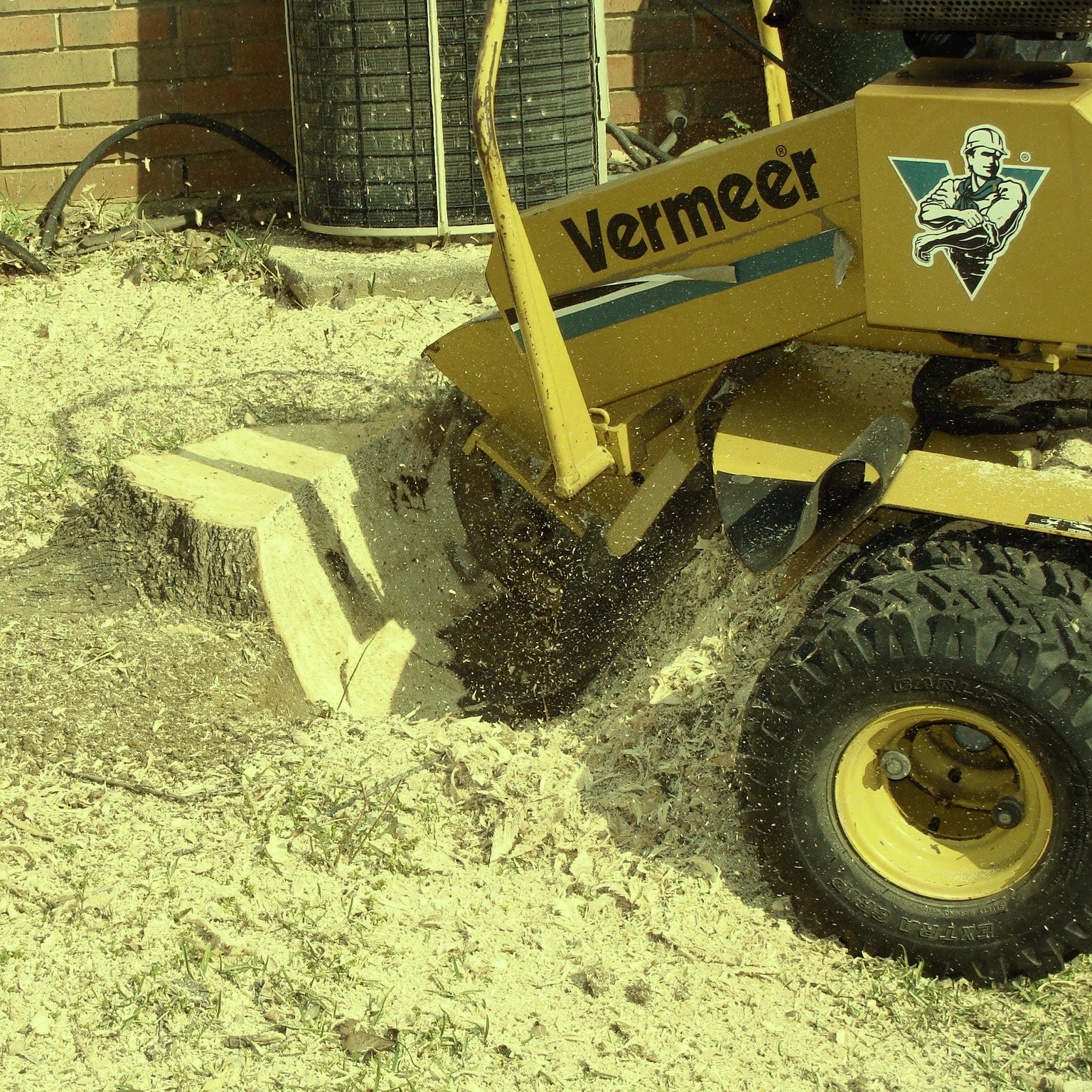 A Vermeer stump grinder cutting a stump with wood chips flying